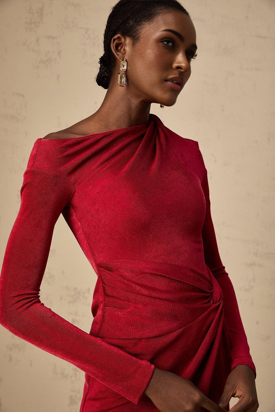 A woman wearing a vibrant red midi dress with a high slit and gathered fabric details