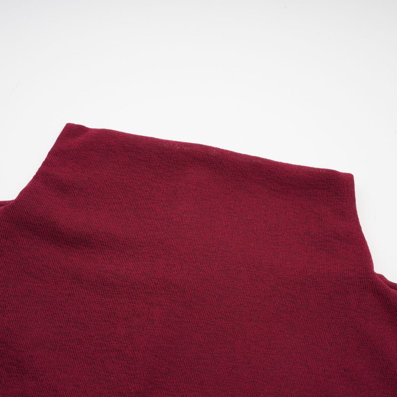 A woman wearing a vibrant red midi dress with ruched detailing and a flap design on the bodice The dress has a form fitting silhouette and falls to mid calf length