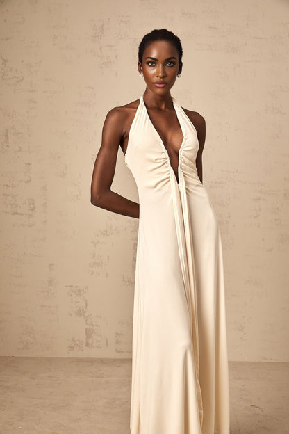 A woman wearing a white floorlength maxi dress with a deep V neckline and draped fabric detail