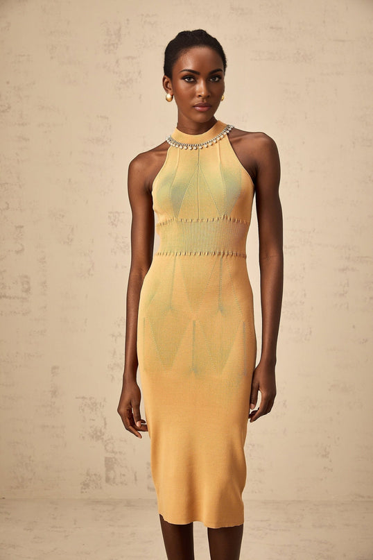 A woman wearing a white knit midi dress with faux pearl embellishments scattered across the fabric