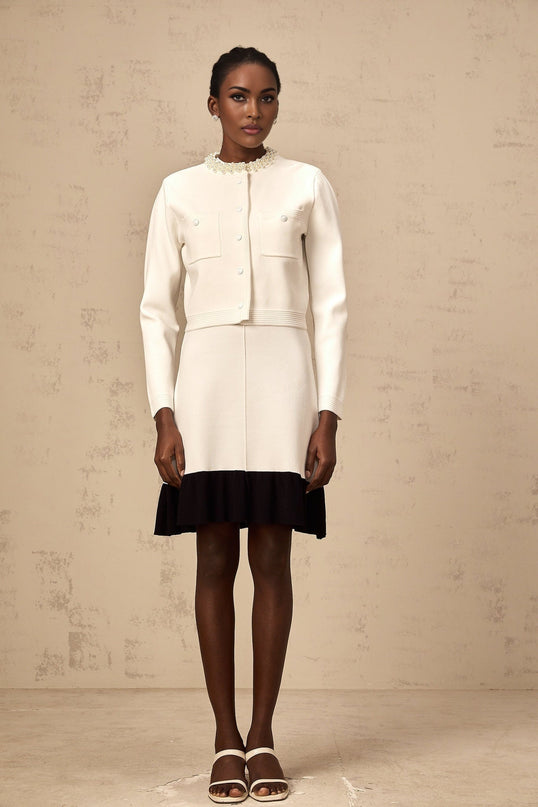 A woman wearing a white knitted cardigan adorned with faux pearl embellishments