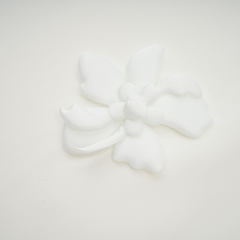 A woman wearing a white midi dress with a square neckline and faux flower details standing in a neutral setting