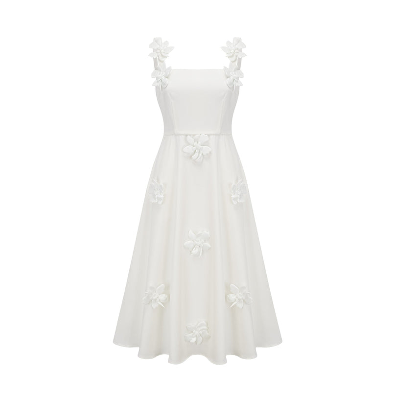 A woman wearing a white midi dress with a square neckline and faux flower embellishments standing in a neutral background