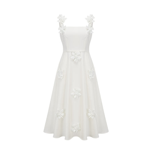 A woman wearing a white midi dress with a square neckline and faux flower embellishments standing in a neutral background