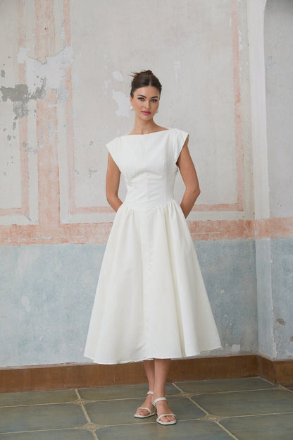 A woman wearing a white midi dress with cap sleeves and an open back design