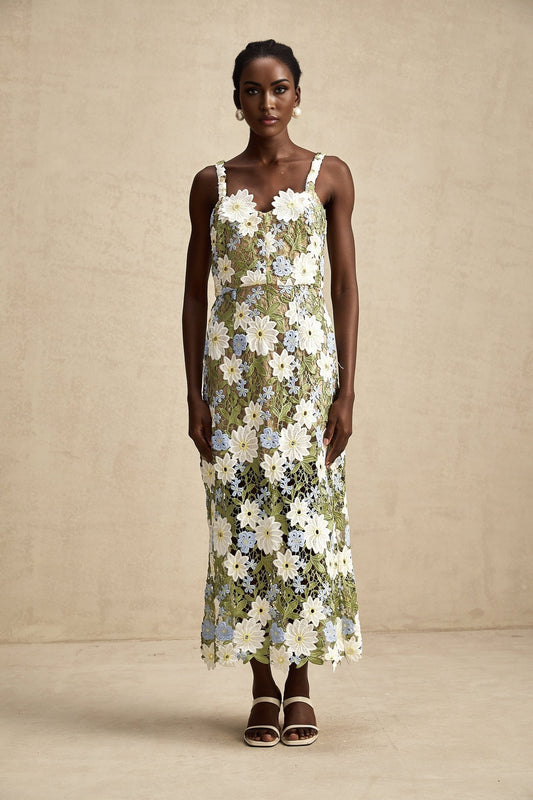 A woman wearing a white midi dress with colorful floral embroidery and delicate hollowcarved patterns throughout the fabric