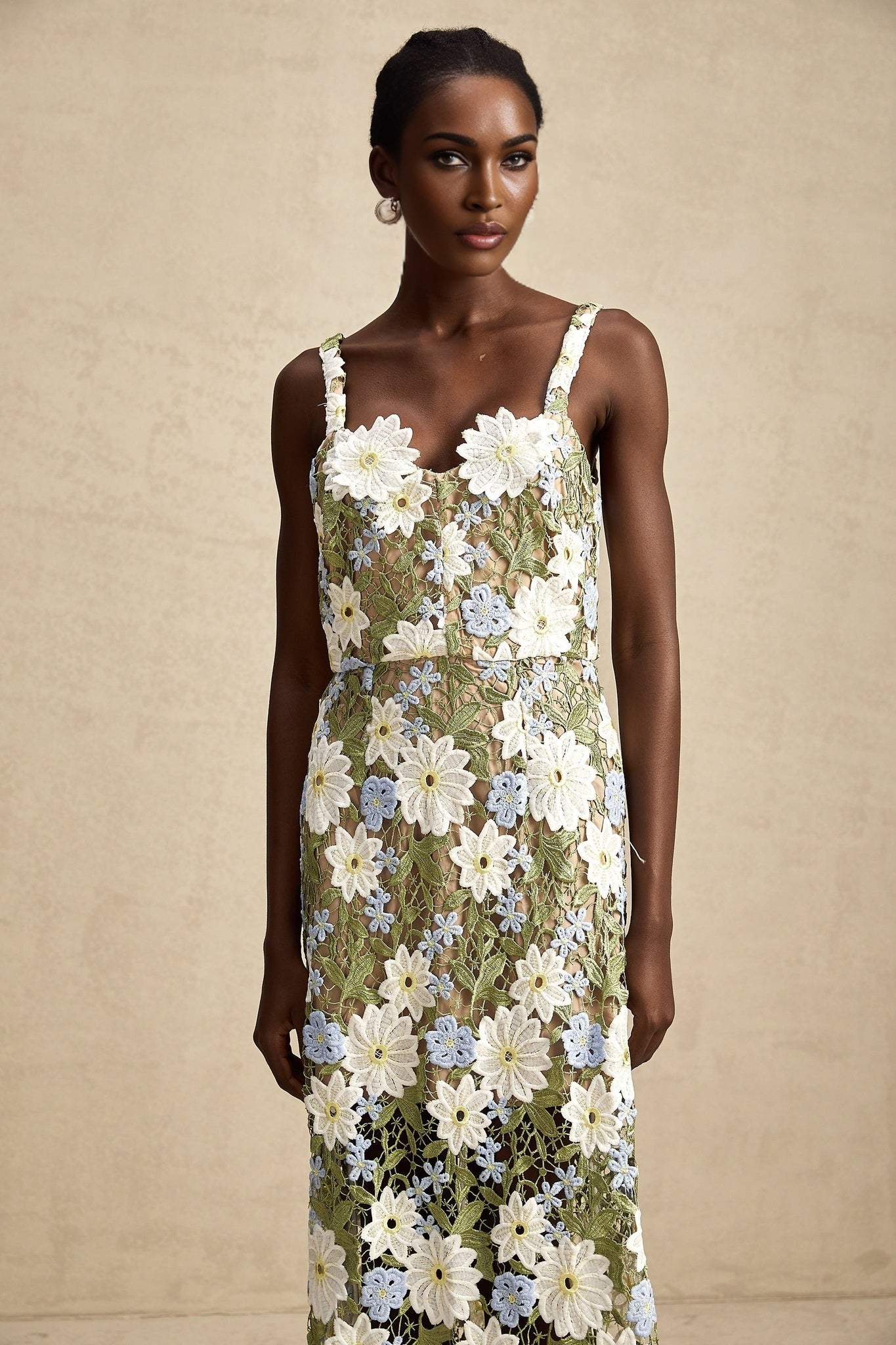 A woman wearing a white midi dress with delicate floral embroidery and hollowcarved details throughout the fabric