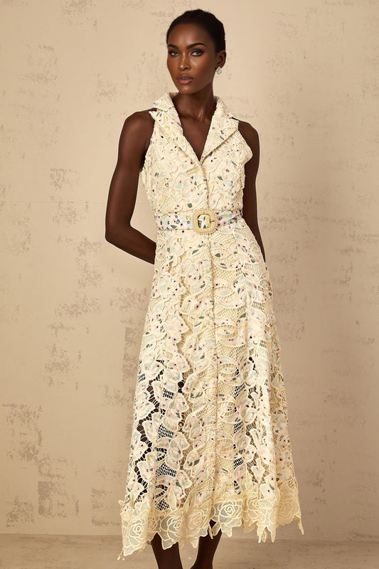A woman wearing a white midi dress with floral embroidery and cutout details standing in a relaxed pose