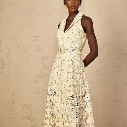 A woman wearing a white midi dress with floral embroidery and cutout details standing in a relaxed pose