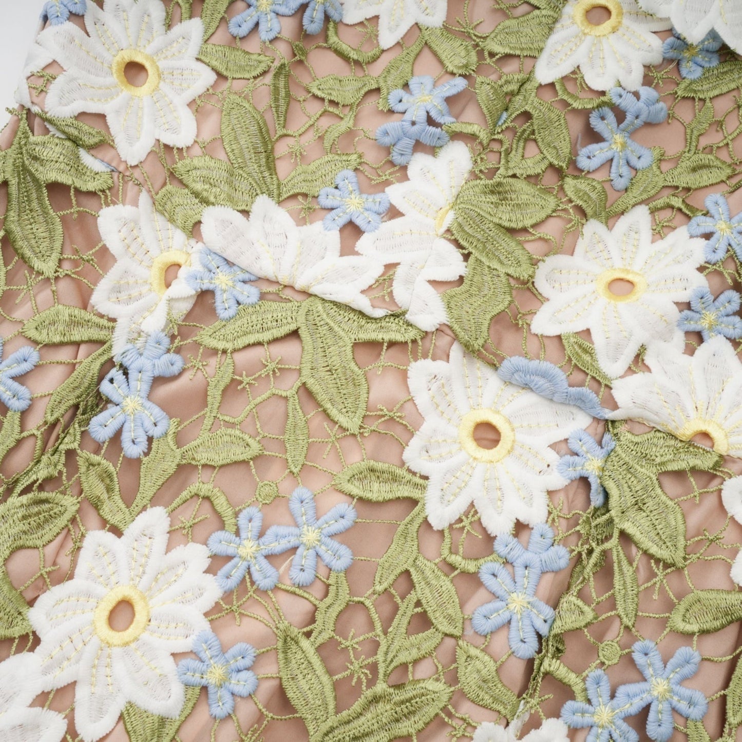 A woman wearing a white midi dress with floral embroidery and cutout details standing in a relaxed pose