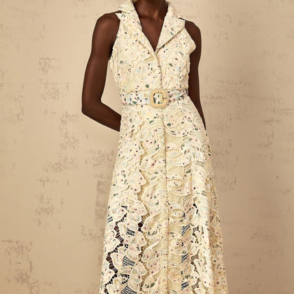 A woman wearing a white midi dress with floral embroidery and cutout details standing in a relaxed pose