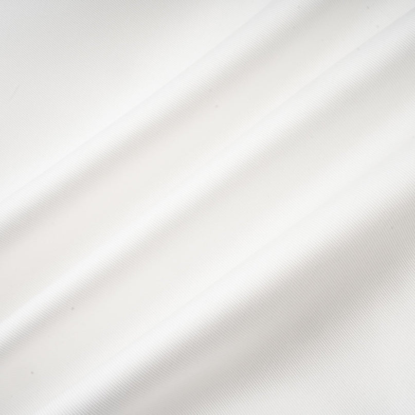 A woman wearing a white offshoulder maxi dress with panels standing against a plain background