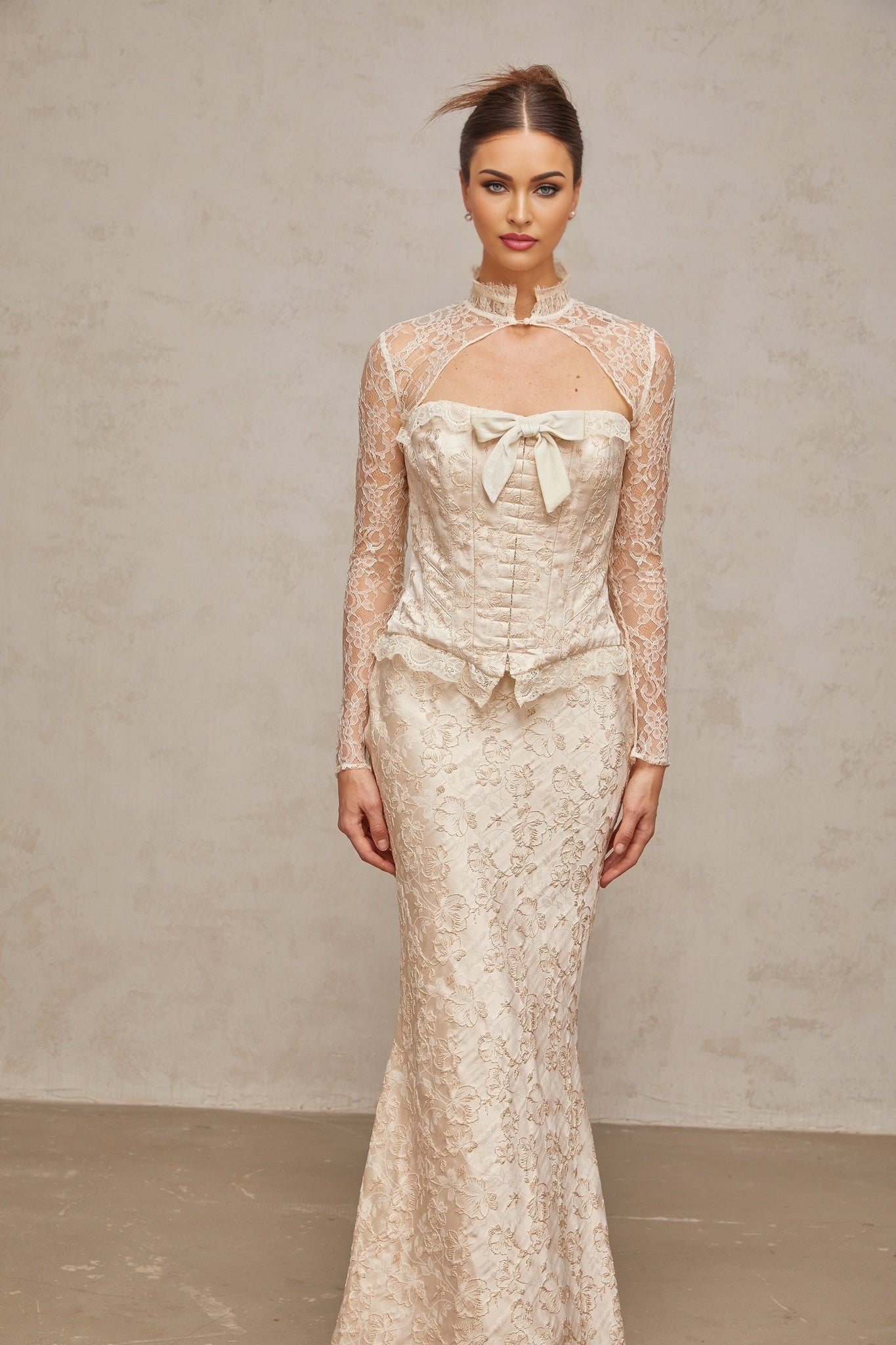 A woman wearing an ivory colored matching set consisting of a patterned jacquard top and skirt the set features a textured floral design and a coordinated elegant look