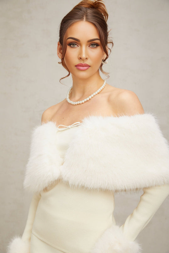 A woman wearing an offwhite matching set consisting of a fineknit top and skirt with faux fur trim