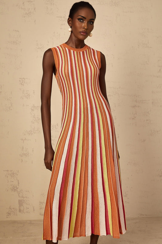 A woman wearing an orange and white vertical striped knit midi dress with long sleeves standing against a plain background