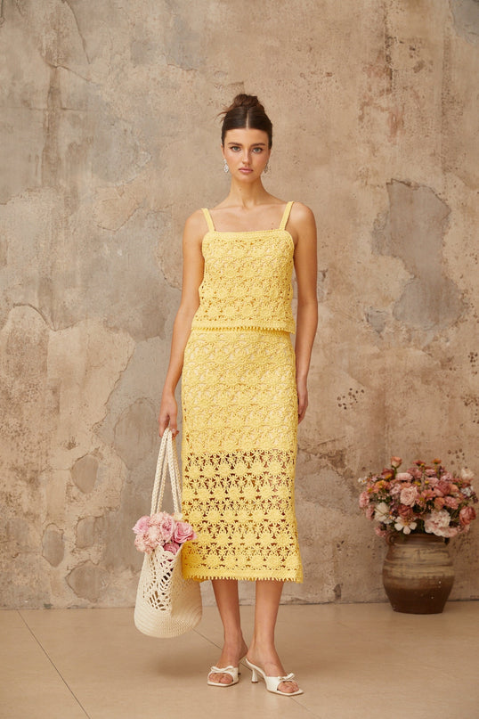 A yellow crochet knit matching set featuring a sleeveless top and mini skirt with an intricate openwork pattern
