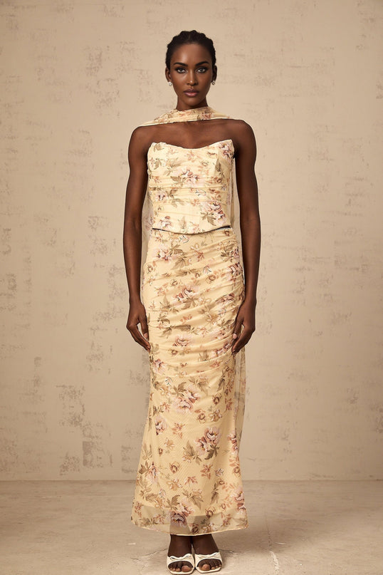 A yellow floral print matching set consisting of a fitted top and skirt worn by a model against a plain background