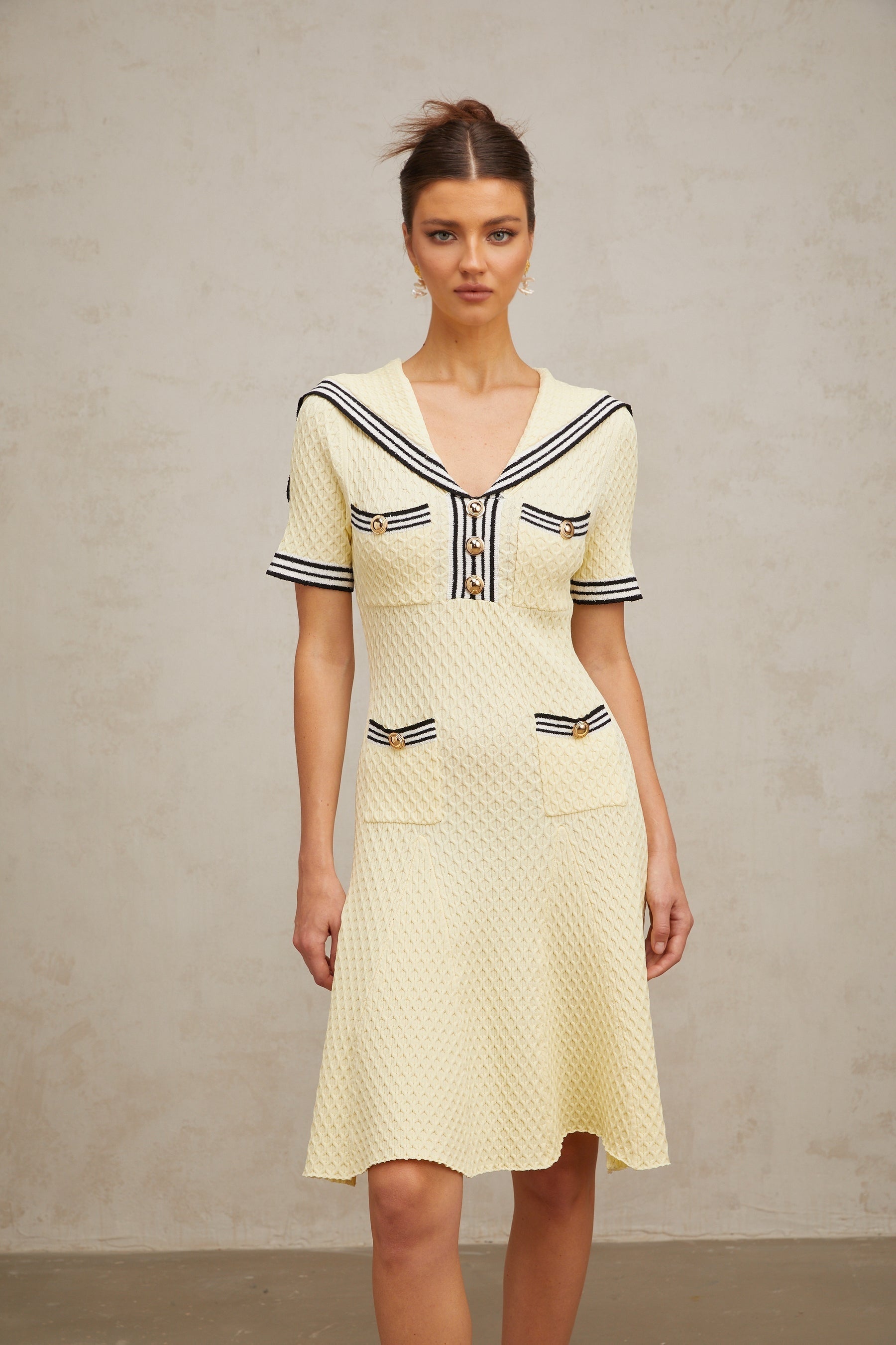 A yellow knitted dress with a sailor collar featuring a Madeleine style design