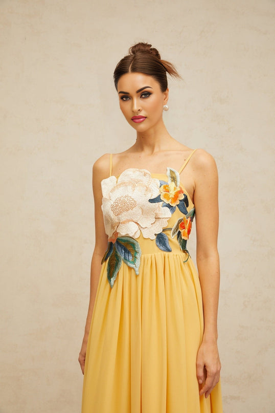 A yellow maxi dress with floral embroidery and shirred detailing called Josette