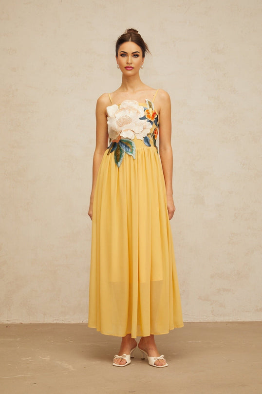 A yellow maxi dress with floral embroidery and shirred detailing named Josette