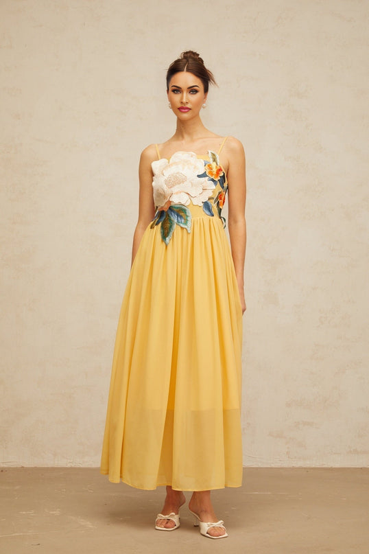 A yellow maxi dress with floral embroidery and shirred detailing named Josette