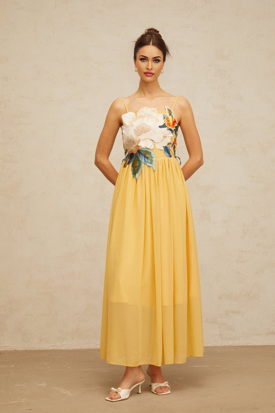 A yellow maxi dress with floral embroidery and shirred details named Josette