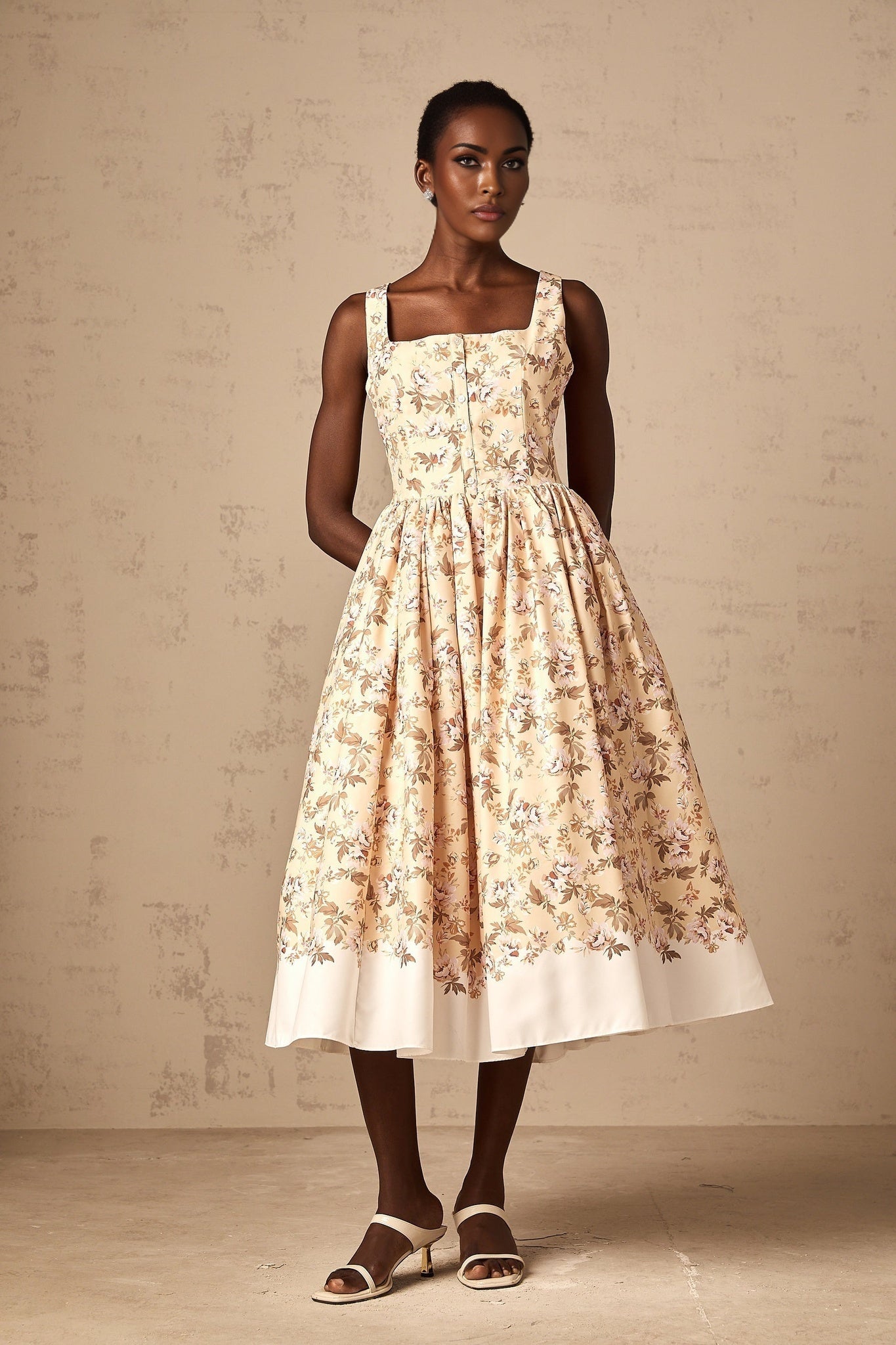 A yellow midi dress with a floral print pattern and button detailing down the front