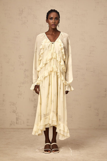 A yellow midi dress with a floral print pattern made of chiffon fabric featuring ruffle details and a flowing silhouette