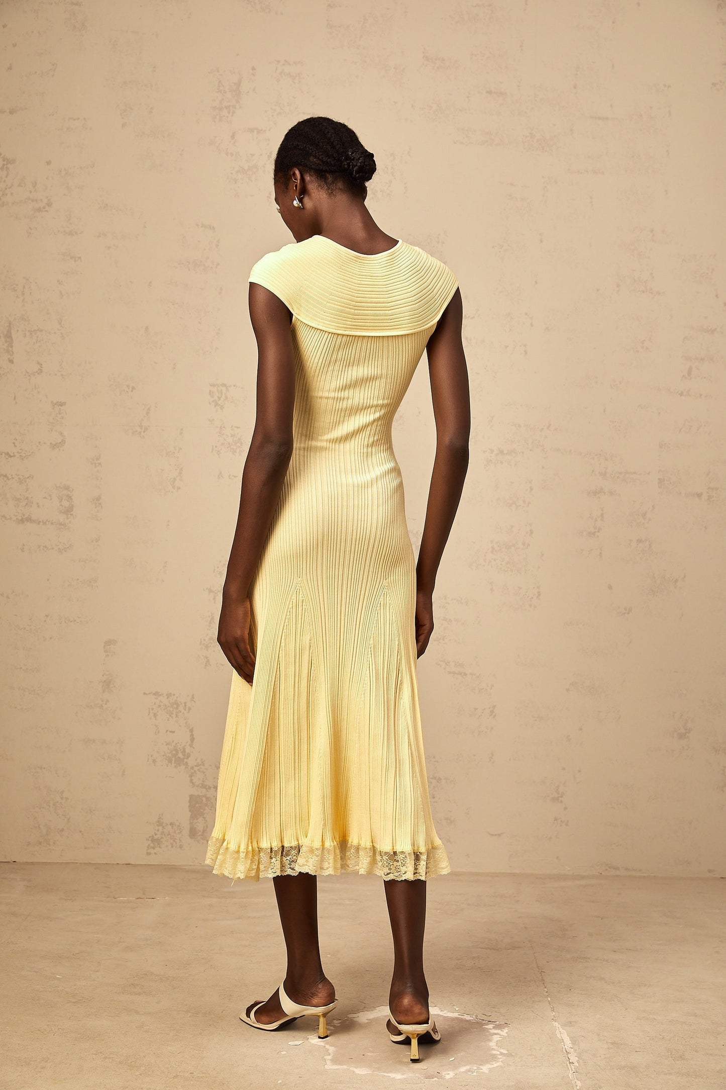 A yellow midi dress with lace panels and ribbed knit fabric featuring a fitted silhouette and delicate details