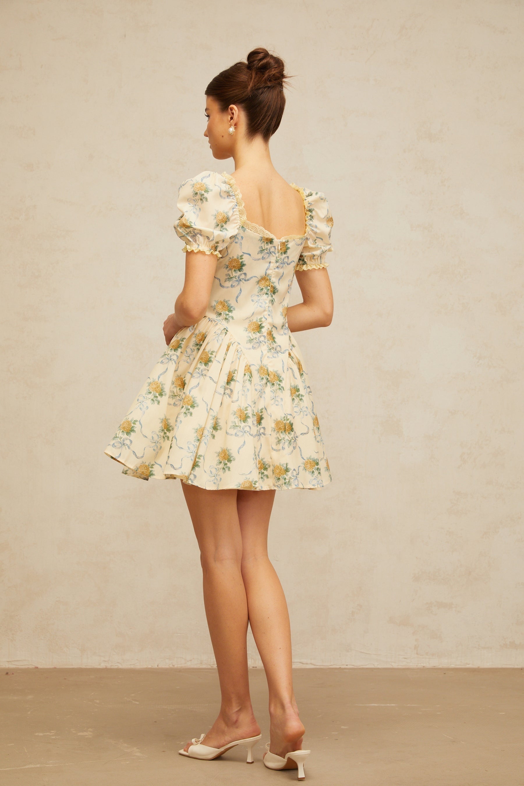 A yellow mini dress with a floral print pattern and shirred detailing named Tiphaine