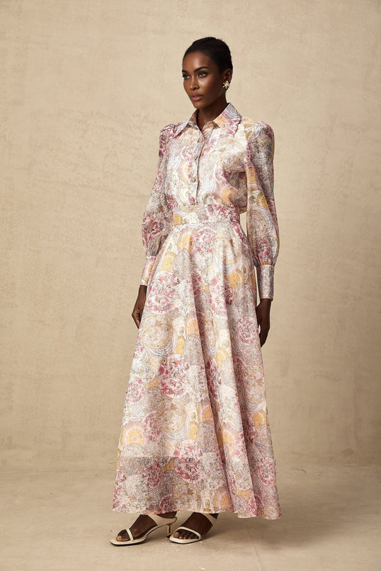 A young girl wearing a cherry pink shirt and skirt set with a pattern print design The shirt has short sleeves and the skirt is knee length Both pieces feature a matching cherry print pattern