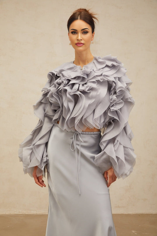 A young girl wearing a light blue blouse with a bow and ruffles paired with a matching skirt featuring a Zelda inspired design