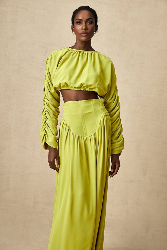 A young girl wearing a matching green outfit consisting of a smocked top and skirt set with a delicate floral pattern