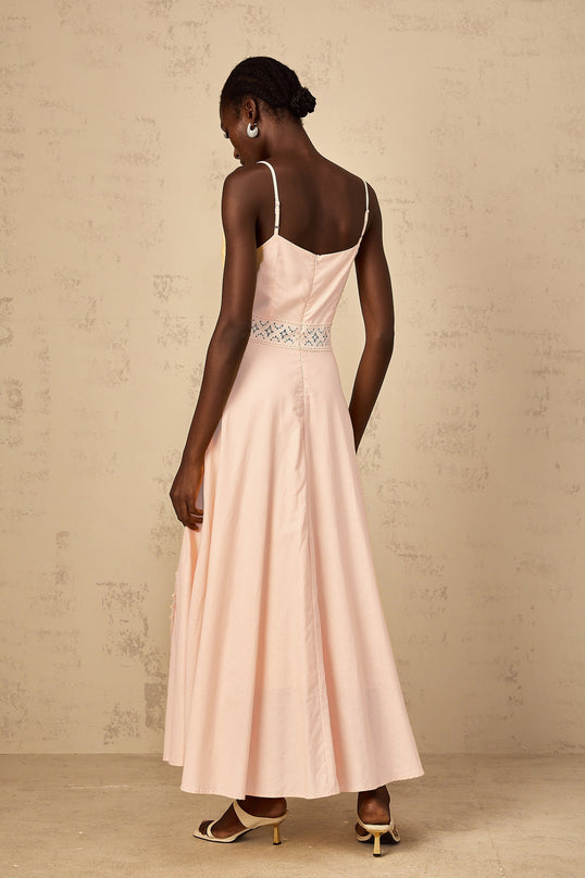 A young girl wearing a pink blouse with floral embroidery paired with a matching dress set featuring the same floral pattern