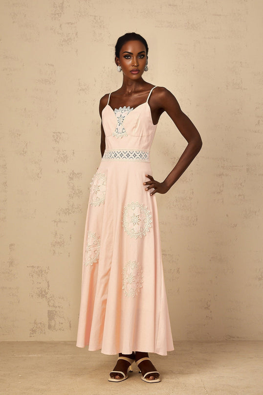 A young girl wearing a pink blouse with floral embroidery paired with a matching dress The set features delicate floral patterns and a soft pink color scheme suitable for special occasions