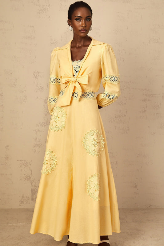 A young girl wearing a yellow blouse and dress set with floral embroidery details The top features short puff sleeves while the dress has a matching floral pattern The outfit is named Romy and is suitable for children