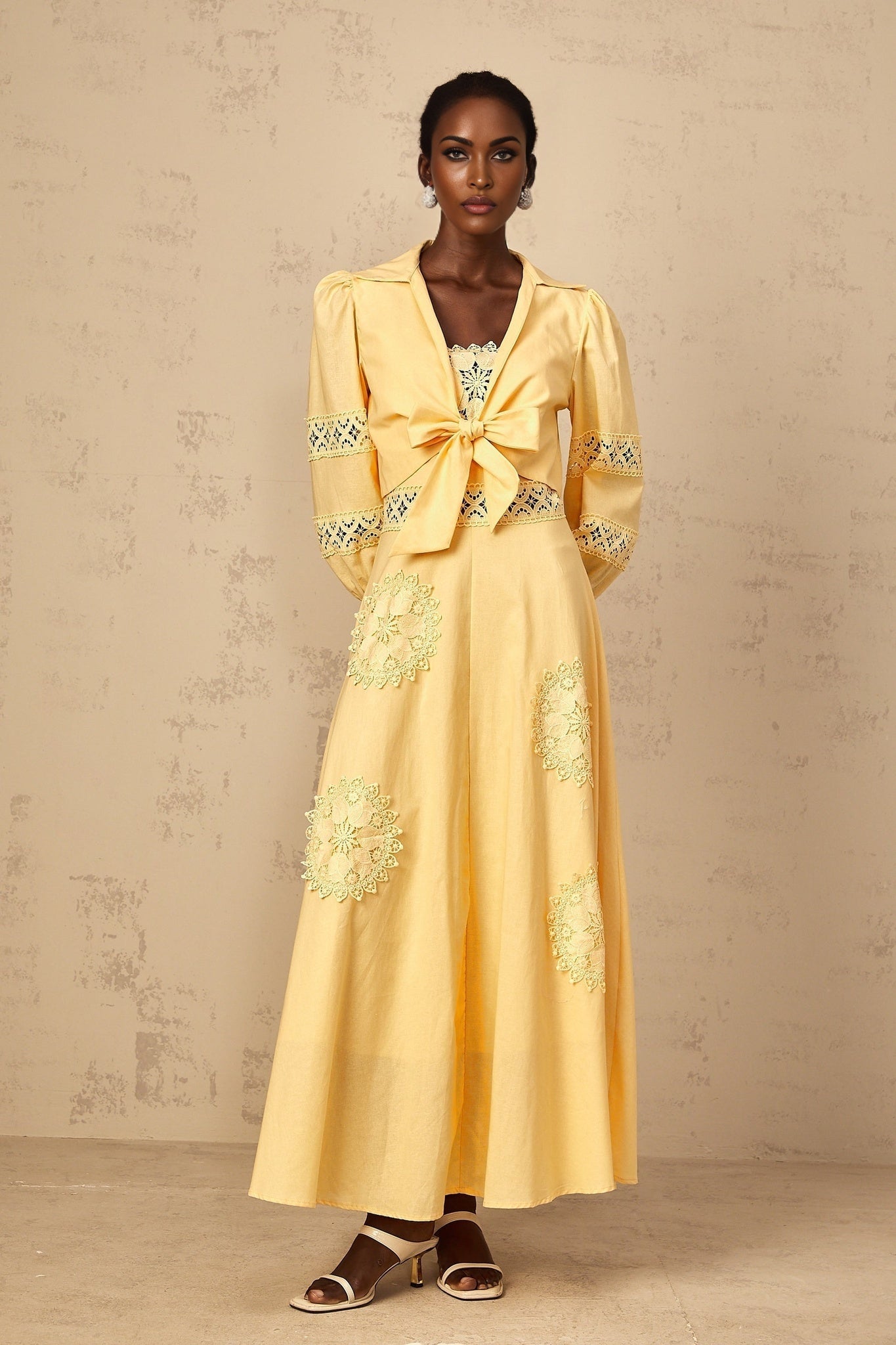 A young girl wearing a yellow dress and blouse set with floral embroidery details The outfit features a sleeveless top and matching skirt in a bright sunny yellow color with colorful flower designs stitched throughout