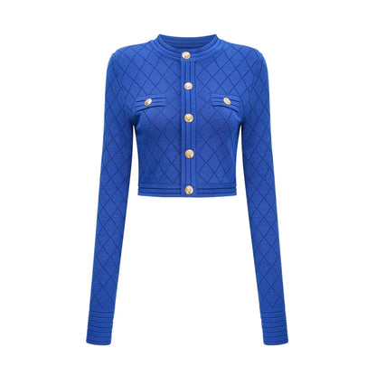 A young woman wearing a blue knitted two piece outfit consisting of a long sleeve top with button details and a matching skirt