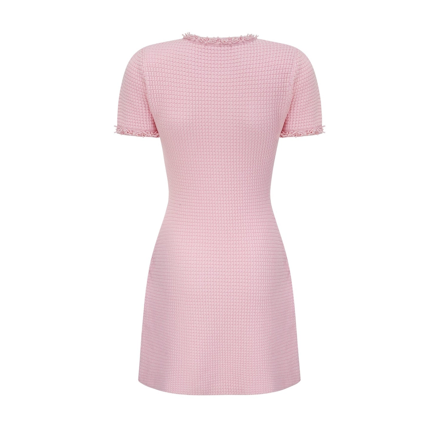 A young woman wearing a short pink knitted dress with beaded embellishments standing against a plain background