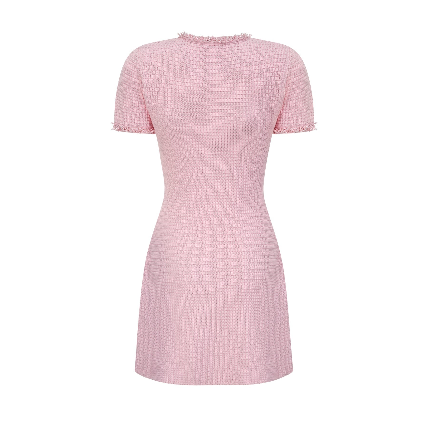 A young woman wearing a short pink knitted dress with beaded embellishments standing against a plain background