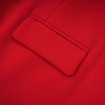 A young woman wearing a vibrant red mini dress with cap sleeves standing against a plain background