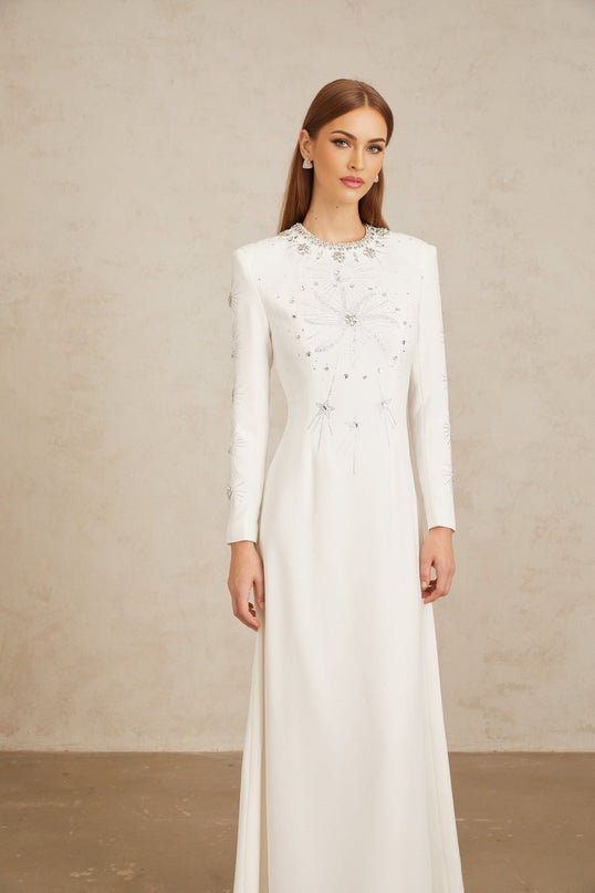 Aloïse White Embellished Maxi Gown in White color with crystal and rhinestone embellishments, round neck, long sleeves, fitted waistline, and flared hem