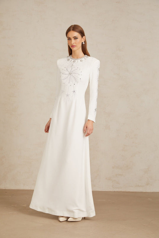 Aloïse White Embellished Maxi Gown in White color with crystal and rhinestone embellishments, round neck, long sleeves, fitted waistline, and flared hem