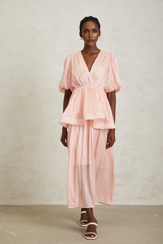 Amalia Maxi Dress in Pink pleated ruffles glossy finish V-neck short puff sleeves chic peplum waist sophisticated silhouette pleated ruffled ruched detailing elegant rear button fastening graceful maxi length 100% Terylene fiber luxurious craftsmanship timeless style