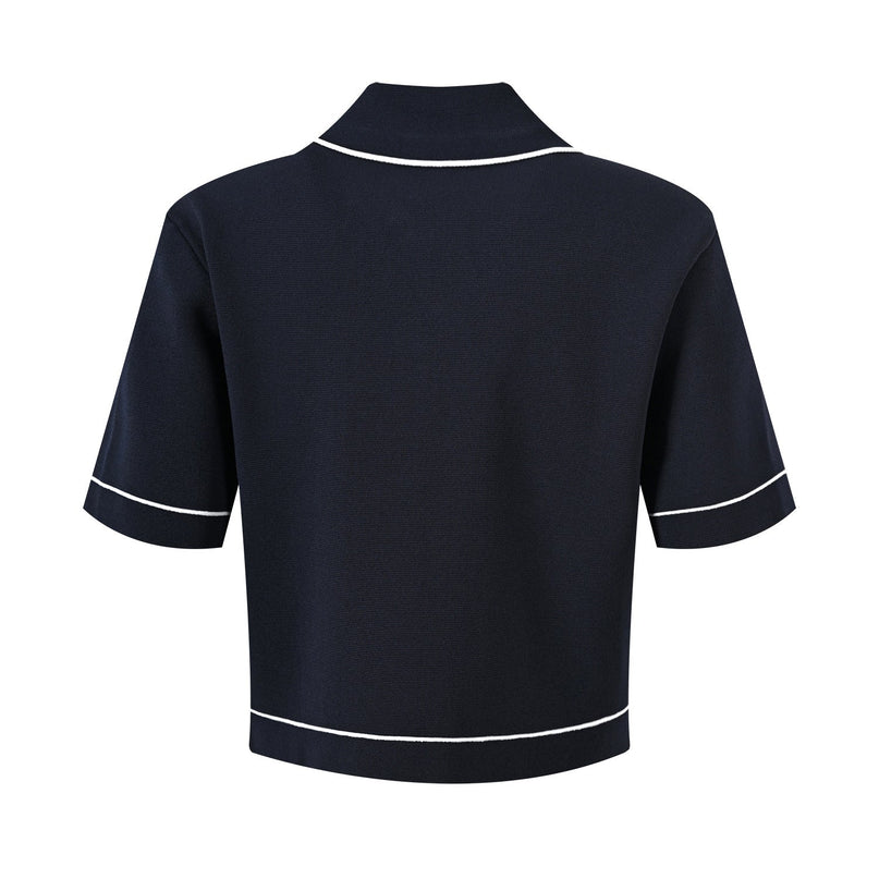 Anita wearing Black polo top with pleated skirt and white accents