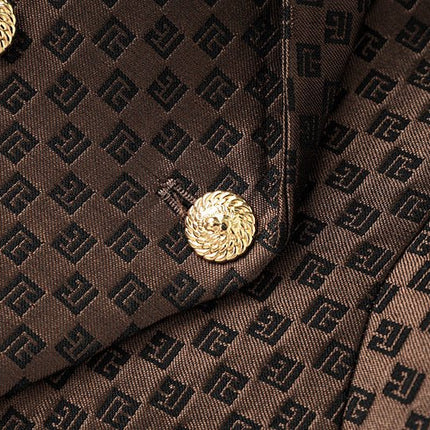 April wearing tailored double-breasted brown blazer with gold buttons and embossed geometric design