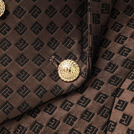 April wearing rich brown tailored double-breasted blazer with gold buttons and embossed geometric design