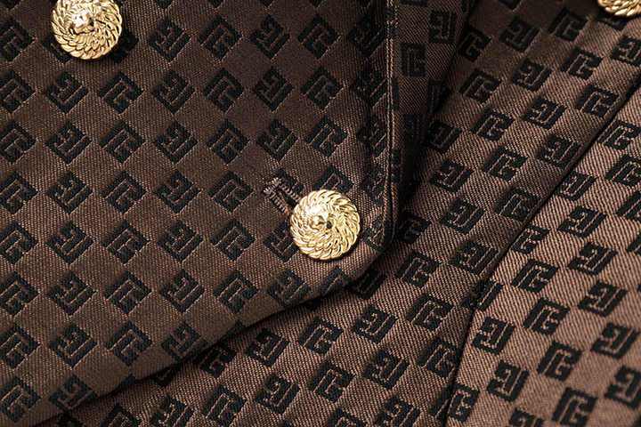 April wearing rich brown tailored double-breasted blazer with gold buttons and embossed geometric design