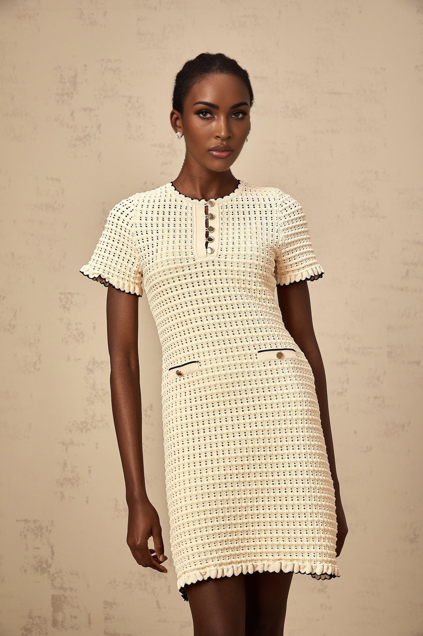 Beige knit mini dress with ruffled details and pointelle pattern featuring short sleeves and a fitted silhouette