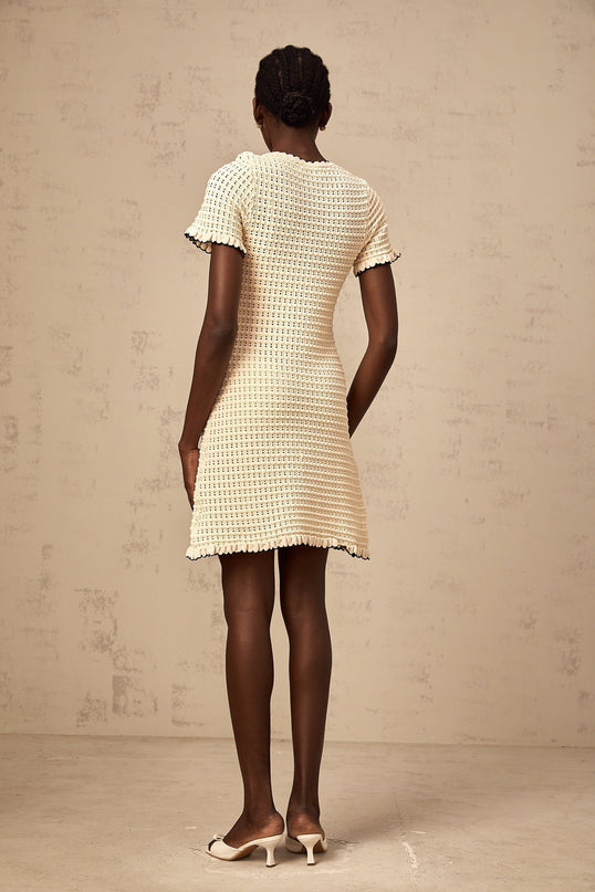 Beige mini dress with ruffled details and pointelle knit pattern featuring short sleeves and a rounded neckline